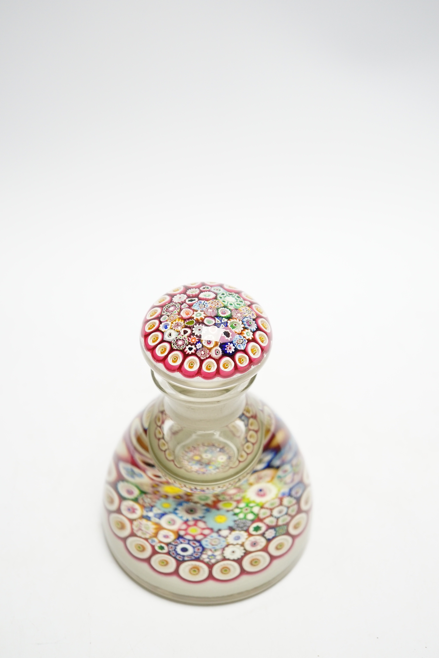 A Paul Ysart close packed millefiori glass inkwell or bottle and stopper, Caithness period, scratched signature ’P. Ysart’ to underside, opaque white ground, 10cm diameter, 13.5cm high